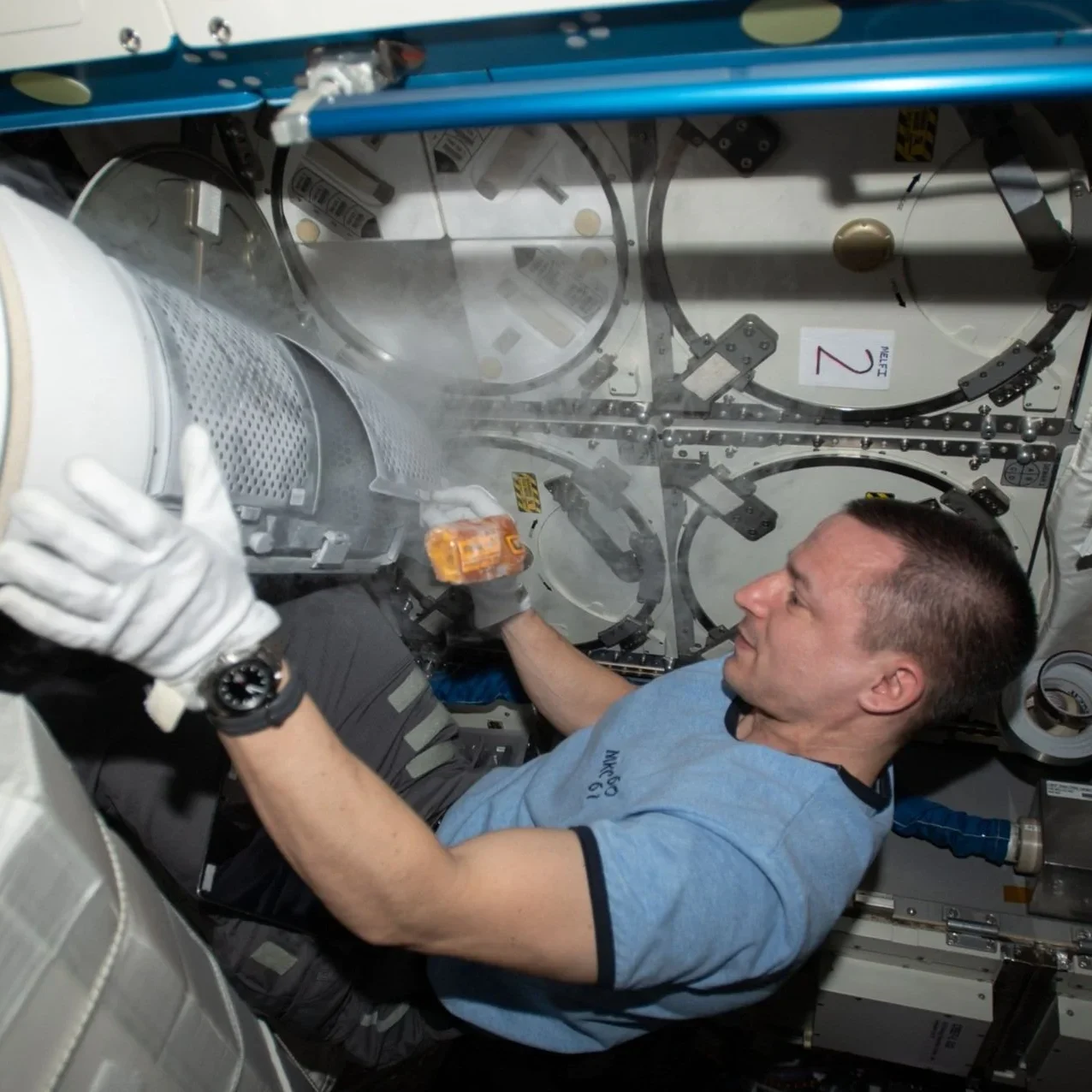 Astronaut working with equipment in space station.