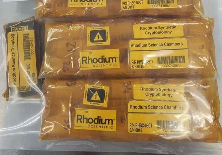 Rhodium Scientific packages with labels on table.